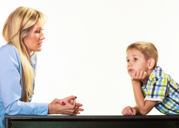 Parenthood domestic life and children upbringing. Mother talking with son little sad boy isolated on white background