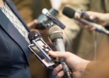 57134905 - group of journalists interviewing politician, holding microphones and voice recorders