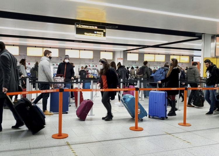 FILE - In this Dec. 20, 2020, file photo, passengers queue for check-in at Gatwick Airport in West Sussex, England, south of London. The United States will require airline passengers from Britain to get a negative COVID-19 test before their flight, the Centers for Disease Control and Prevention announced late Thursday, Dec. 24. The US is the latest country to announce new travel restrictions because of a new variant of the coronavirus that is spreading in Britain. (Gareth Fuller / PA via AP)
