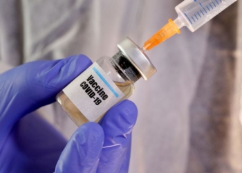 FILE PHOTO: A woman holds a small bottle labeled with a "Vaccine COVID-19" sticker and a medical syringe in this illustration taken April 10, 2020. REUTERS/Dado Ruvic/Illustration/File Photo