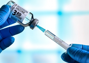 doctor with Coronavirus vaccine bottle with the name of the 3rd dose of vaccine on the label. Doctor preparing a dose for a patient of the third vaccine for Covid-19