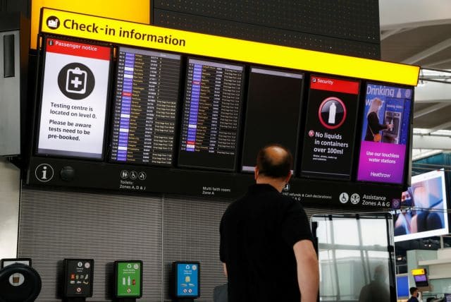 FILE PHOTO: A man looks at a check-in information board in the departures area of Terminal 5 at Heathrow Airport in London, Britain, May 17, 2021. REUTERS/John Sibley/File Photo