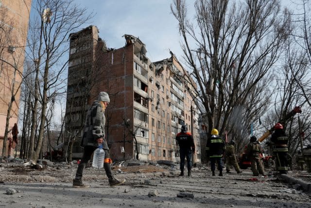 A woman carries a bottle of water as emergency specialists work at a residential building damaged by shelling during Ukraine-Russia conflict in the separatist-controlled city of Donetsk, Ukraine March 30, 2022. REUTERS/Alexander Ermochenko