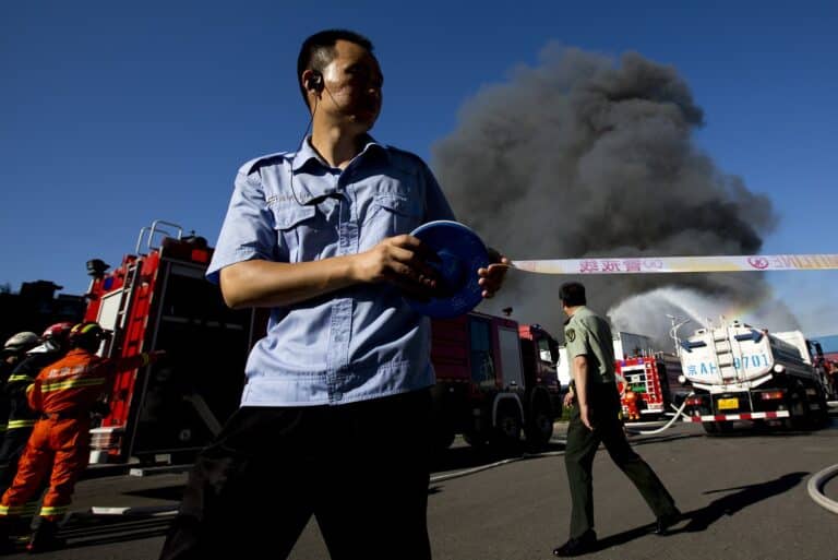 Policemen prepare to set up a line to keep away the onlookers as firemen extinguish a fire on a lumberyard at the south side of Beijing, China, Tuesday, June 30, 2015. The cause of the fire on the lumberyard is under investigation and no casualties have been reported, according to Beijing Fire Department. (AP Photo/Andy Wong)