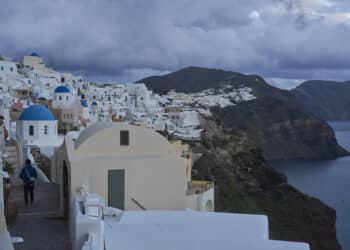 A tourist approaches blue-domed Orthodox churches in the town of Oia on the earthquake-struck island of Santorini, Greece, Tuesday, Feb. 4, 2025. (AP Photo/Petros Giannakouris)