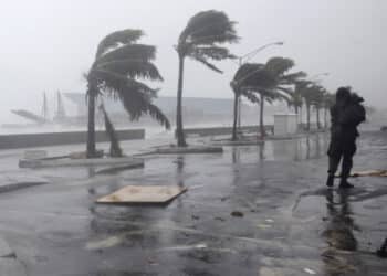A man walks along the waterfront as Hurricane Irene passes to the east of Nassau on New Providence Island in the Bahamas, Thursday Aug. 25, 2011.  Irene is pounding the Bahamas as a Category 3 hurricane. (AP Photo/Lynne Sladky)